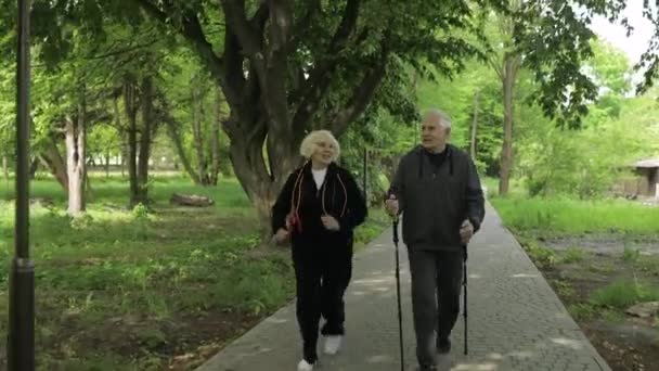 Aktivní starší pár. Muž trénink Nordic walking, žena běží v parku