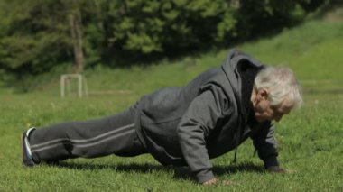 Aktif kıdemli yaşlı adam spor alanında şınav çekiyor.