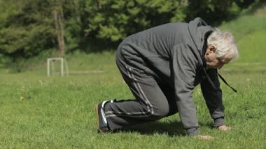 Aktif kıdemli yaşlı adam spor alanında şınav çekiyor.