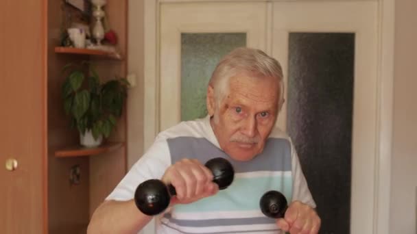 Senior elderly caucasian man doing sports exercises with dumbbells at home — 비디오