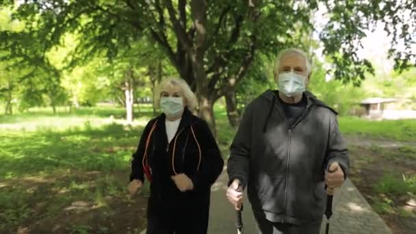 Aktiv äldre man, kvinna utbildning Nordic walking in park under karantän — Stockvideo