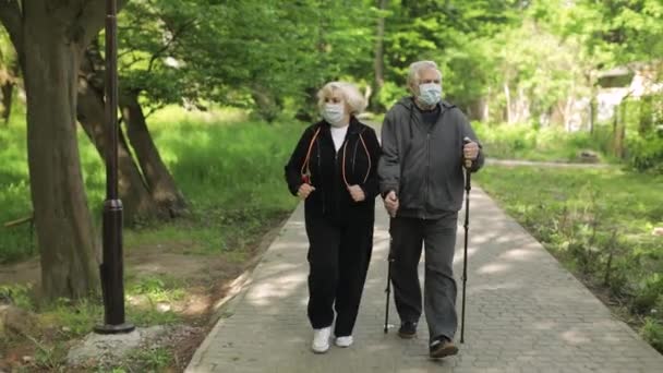 Vieil homme actif, femme s'entraînant à la marche nordique dans le parc pendant la quarantaine — Video