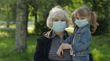 Yaşlı büyükanne ve torunu parkta maske takıyor. Coronavirüs