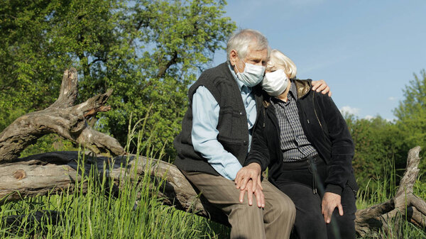 Senior couple in medical masks during COVID-19 coronavirus quarantine in park