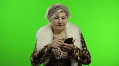 Akıllı telefonlarda sosyal medya uygulaması kullanan Kafkas bir büyükanne kadın.