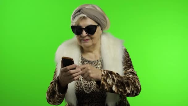 Äldre eleganta trendiga kaukasiska mormor kvinna med hjälp av smartphone. Kromnyckel — Stockvideo