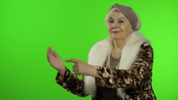 Ältere stilvolle Großmutter. Kaukasische Frau zeigt mit der Hand auf etwas