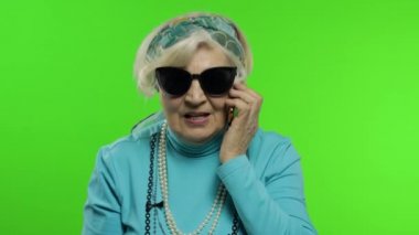 Yaşlı, şık, Kafkas büyükanne kadın cep telefonuyla konuşuyor. Krom anahtar