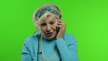 Yaşlı, şık, Kafkas büyükanne kadın cep telefonuyla konuşuyor. Krom anahtar