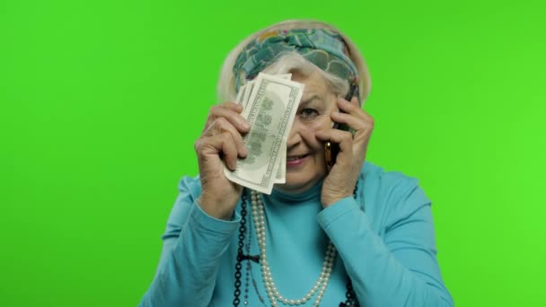 Elderly caucasian grandmother woman with money banknotes talking on mobile phone — Stock Video