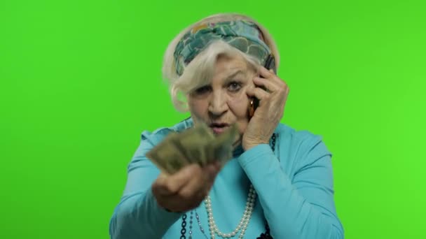 Elderly caucasian grandmother woman with money banknotes talking on mobile phone — Stock Video