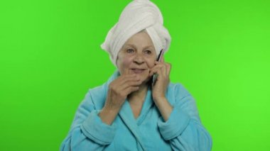 Duştan sonra yaşlı büyükanne. Cep telefonuyla konuşan yaşlı bir kadın. Krom anahtar