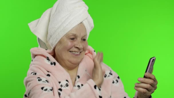 Grand-mère âgée en peignoir. Vieille femme utilisant le téléphone mobile pour appel vidéo — Video