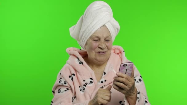 Äldre mormor i badrock. Gammal kvinna som använder sociala medier app på smartphone — Stockvideo