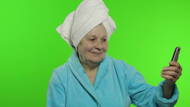 Abuela mayor después de la ducha. Vieja mujer haciendo selfies usando teléfono móvil — Vídeo de stock