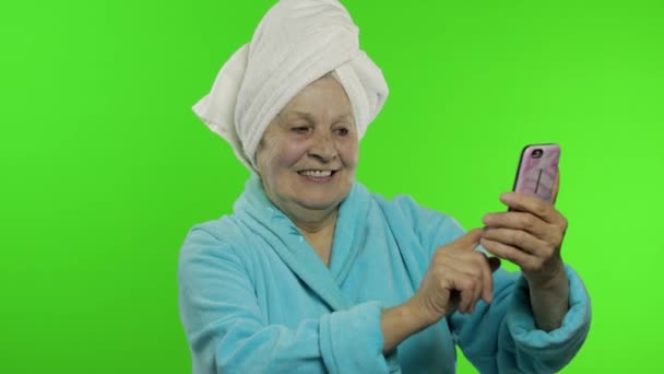 Elderly grandmother after shower. Old woman making selfies using mobile phone — Stock Video