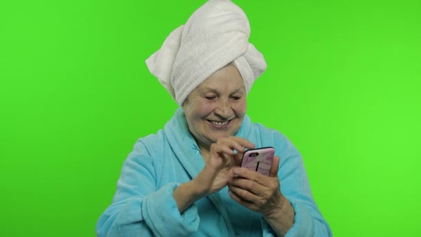 할머니는 샤워하고 나서. 온라인 쇼핑을 위해 스마트폰을 사용하는 할머니 — 비디오