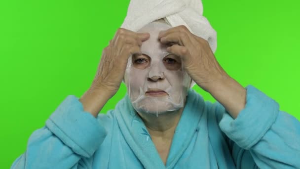 Літня бабуся після душу. Стара жінка застосовує косметичну маску для обличчя — стокове відео
