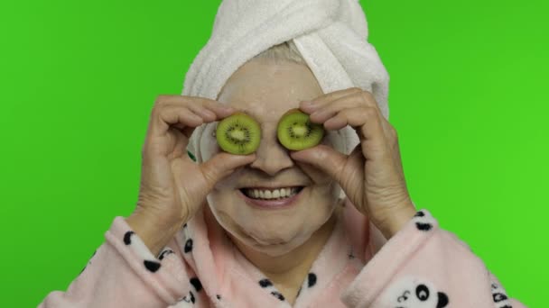 Anziana nonna in accappatoio con maschera a bolle. Vecchia donna con kiwi — Video Stock