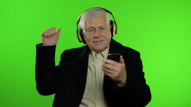 Yaşlı beyaz büyükbaba dans ediyor, kutlama yapıyor, müzik dinliyor. Krom anahtar