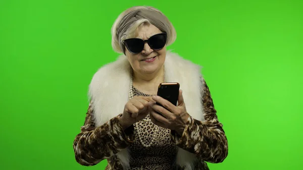 Anziani alla moda donna nonna caucasica alla moda utilizzando smartphone. Chiave cromatica — Foto Stock