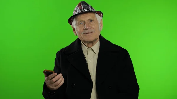 在智能手机上使用社交媒体应用程序的老年时尚的高加索祖父 — 图库照片