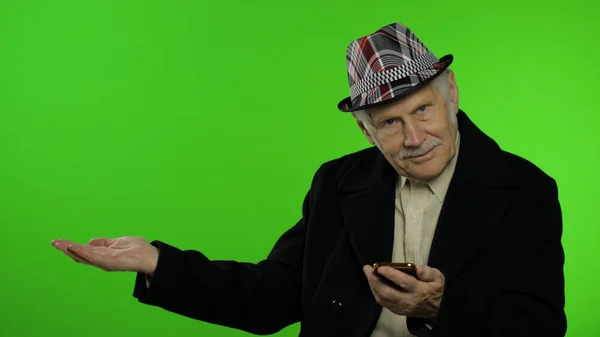 Anciano abuelo caucásico usando smartphone, apuntando a algo con la mano — Foto de Stock