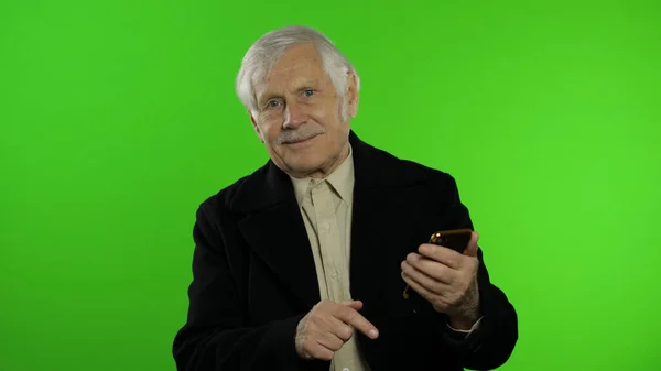 スマートフォンのソーシャルメディアアプリを使用して高齢者スタイリッシュな白人祖父男 — ストック写真