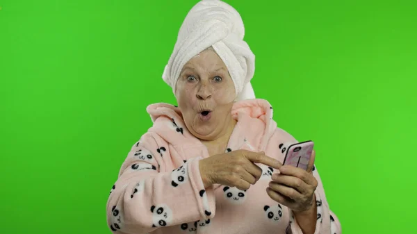 Äldre mormor efter dusch. Gammal kvinna som använder smartphone för online shopping — Stockfoto