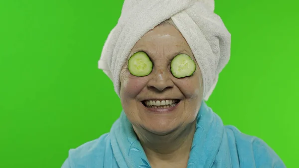 Abuela anciana en albornoz después de la ducha. Vieja con rodajas de pepino — Foto de Stock