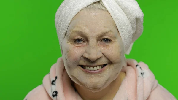 Elderly grandmother after shower. Old woman applying cosmetic bubble face mask — Stock Photo, Image