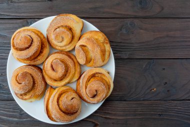 Beyaz tabakta taze pişmiş tarçınlı çörekler. Çıtır çörekler.