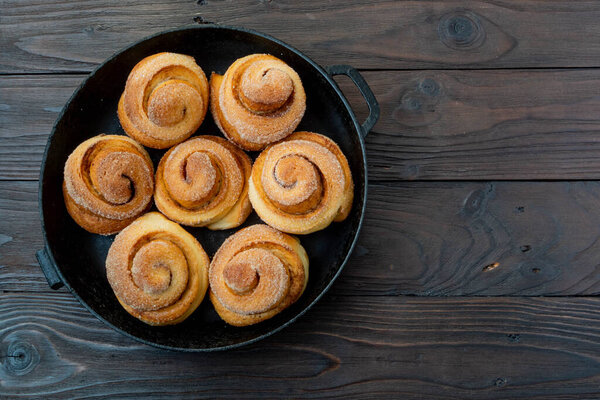 Delicious homemade cinnamon muffins bun in a circle shaped baking tray on a brown wooden background. Horizontal image. Macro shot.