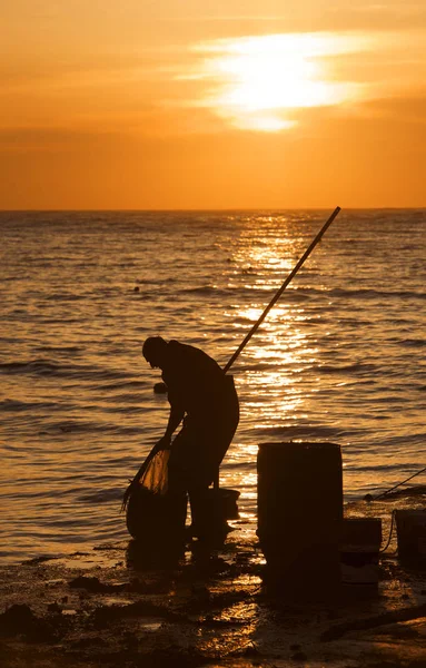 silhouette of fisherman working near the sea in sunrise time. Daily routine of fisherman. Sunrise in Marsascala, Malta