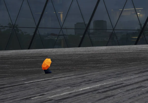 Otoño. Una mujer sentada en el suelo de madera en días lluviosos. Mujer con paraguas amarillo. Un día lluvioso en la ciudad. Temporada de lluvias. Mal tiempo. Vilna, Lituania — Foto de Stock