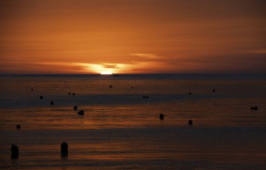 Marsascala, Malta 'da kızıl gün doğumu. Thomas Körfezi, Marsaskala, Malta. Arka planda teknesi olan doğal gün batımı.