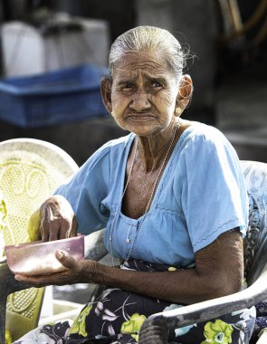Negombo 'daki balık pazarında sokakta yemek yiyen yaşlı Sri Lankalı kadının portresi. Güzel bir dinlenme ve ara verdiğimizde sokak pazarında öğle yemeği.