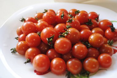 Beyaz tabakta küçük kırmızı domatesler.