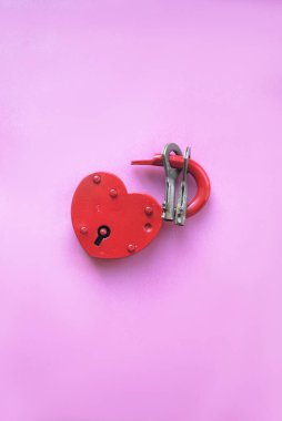 Pembe arka planda anahtarlı kırmızı kalp şeklinde kilit