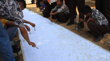 Yerel bir okulda, Batang Endonezya 'da, 4 Aralık 2019' da uzun bir kumaşta batik yaparken özel ihtiyaçları veya engelleri olan okul öğrencileri