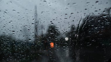 Bulanık arabalar ve trafik ışıkları. Ön cam camına yağmur damlaları
