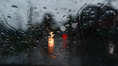 Bulanık arabalar ve trafik ışıkları. Ön cam camına yağmur damlaları