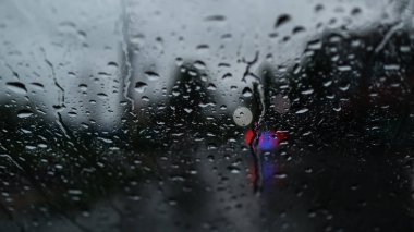 Bulanık arabalar ve trafik ışıkları. Ön cam camına yağmur damlaları