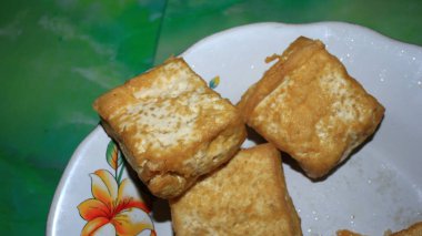 Görüntü bulanık. Beyaz bir tabakta kızarmış tofu. Seçici bir odak noktasıyla fotoğraflanmış.