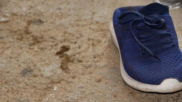 Blurred image out of focus images blue colored plastic shoes on a dirty cement floor