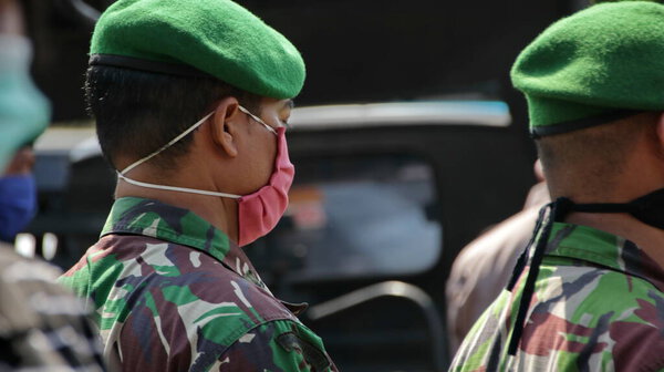 BLURRY and soft focus images members of the army and police wear masks, in their activities to avoid опасный вирус, Peepongan Indonesia, April 10, 2020
