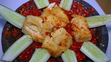 Baharatlı sambal ve taze salatalık dilimleriyle servis edilen kızarmış tofu, nehir taşından bir havan topu.
