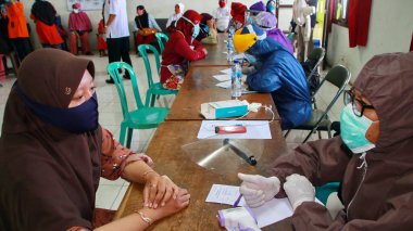 Toplum, Batang, Endonezya, 27 Mayıs 2020 'de hızlı bir test yaparken bulanık seçici odaklanma ve gürültü imajı çalışanları