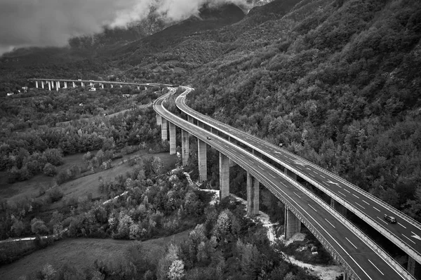 Negro y withe foto de la carretera de velocidad alpina en Italia. Vista aérea desde arriba con nubes en el fondo — Foto de Stock