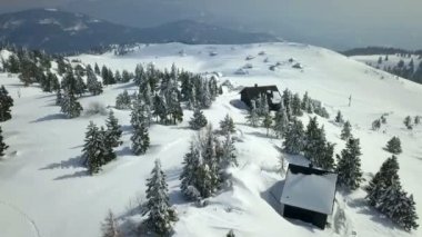 Dağların tepesinde sadece iki dağ kulübesi var. Hava görüntüsü. Kış mevsimindeyiz ve ülkenin çoğu karla kaplı..